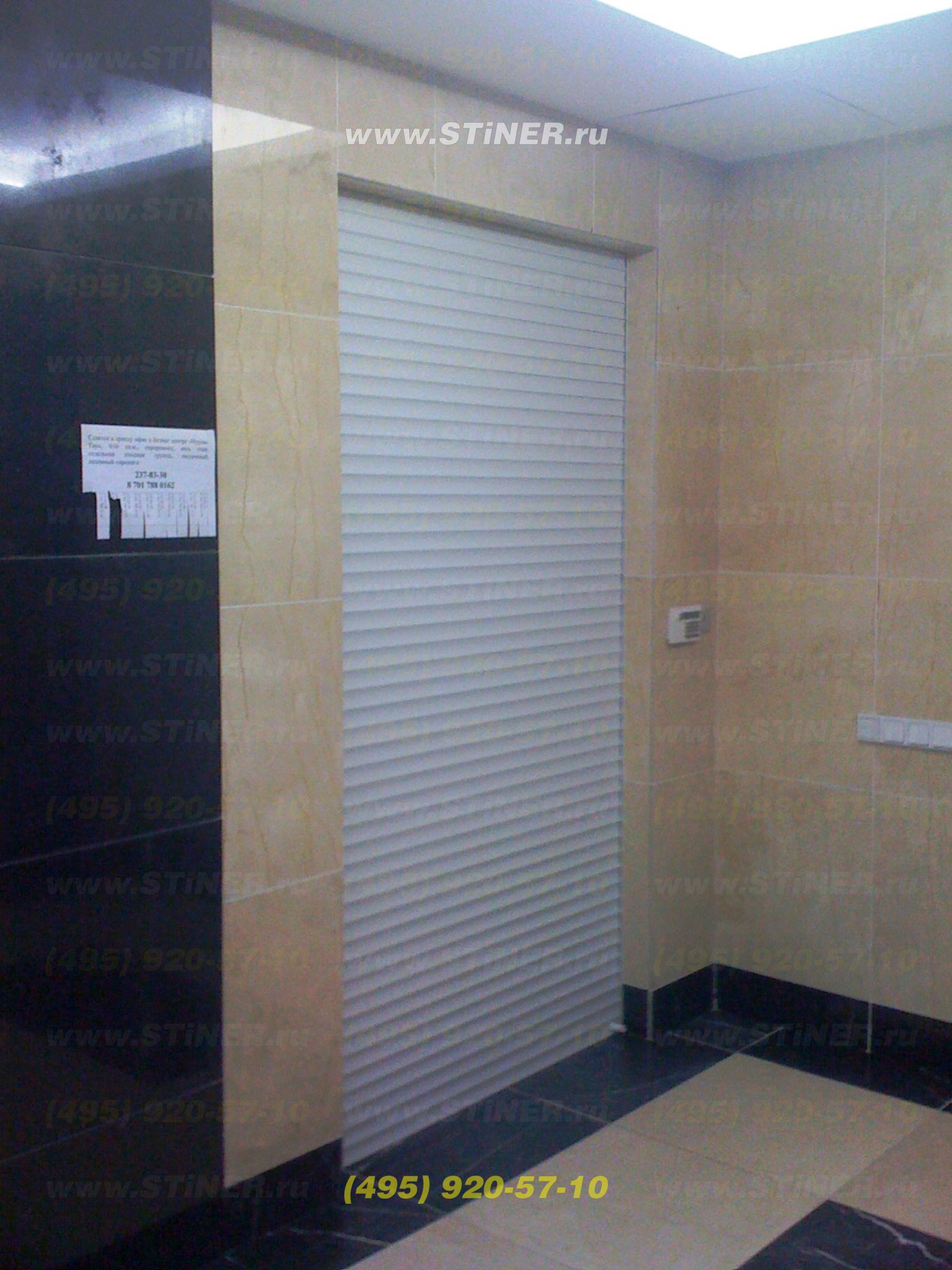 White shutters built into wall in the office building. Electric rolling shutters with remote control